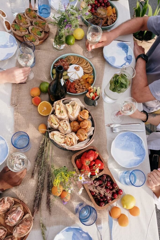 A lively group lunch event organized by Breaking Bread Matchmaking with diverse middle-aged individuals enjoying a meal outdoors in a scenic setting